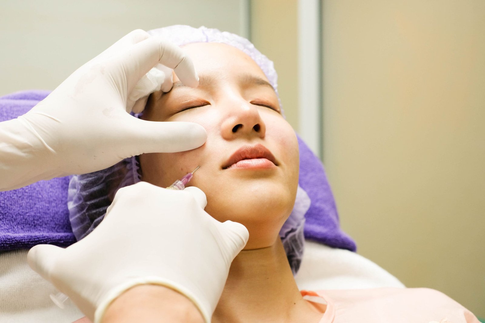 Doctor Hands with Syringe and Needle Injecting on Asian Women Face at Clinic